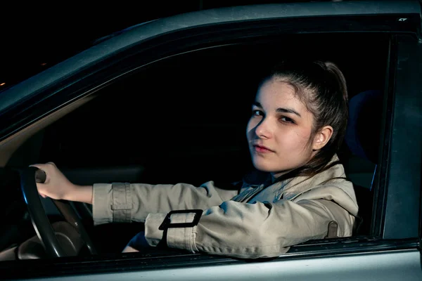 The girl behind the wheel of the car looks out the window — Stock Photo, Image