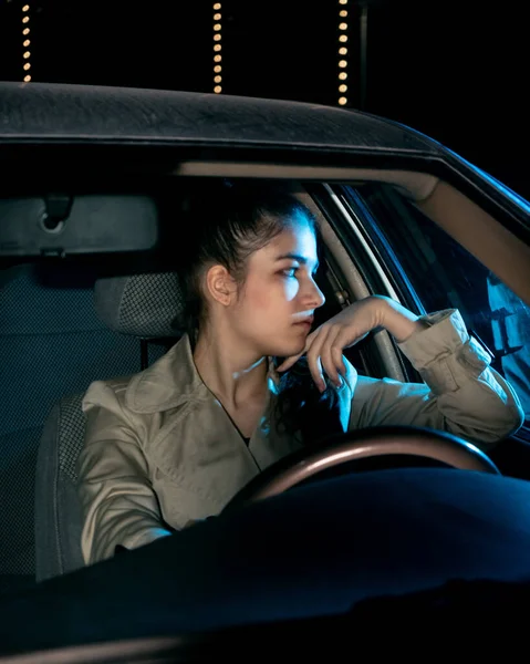Dziewczyna za kierownicą samochodu wygląda przez okno. — Zdjęcie stockowe