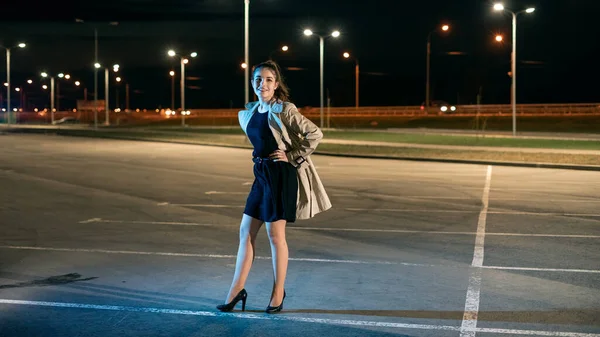 Chica en abrigo beige y vestido contra el telón de fondo de la ciudad de la noche — Foto de Stock