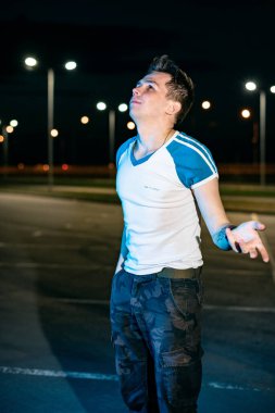 Geceleri otoparkta fenerlerin arkasında duran adam.