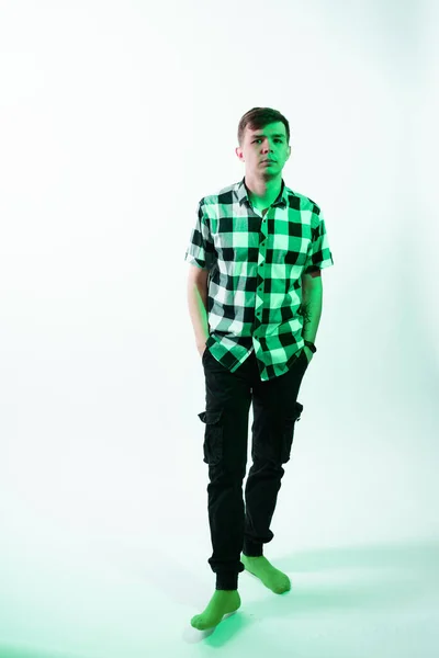 Porträtt av en ung man upplyst av grönt ljus, mot en vit bakgrund — Stockfoto
