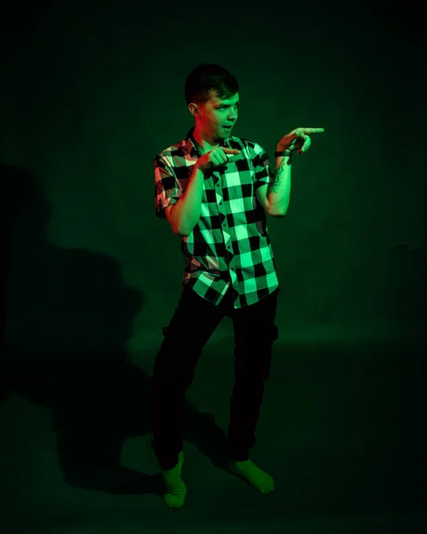 Портрет парня в клетчатой рубашке с красным и зеленым светом на черном фоне — стоковое фото