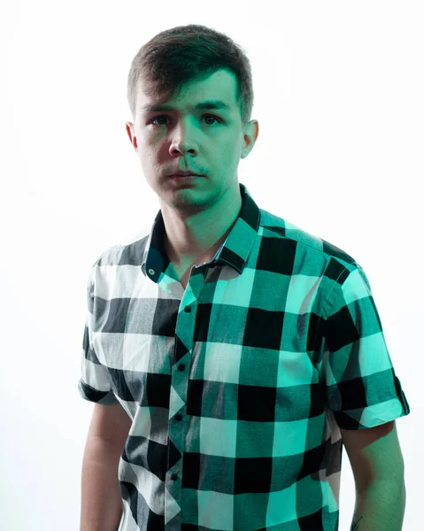 Porträtt av en ung man upplyst av grönt ljus, mot en vit bakgrund — Stockfoto