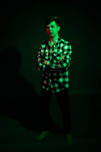 Porträtt av en kille i rutig skjorta med rött och grönt ljus på en svart bakgrund — Stockfoto