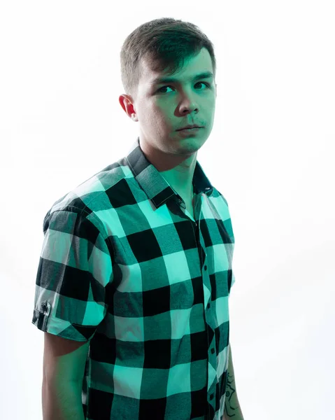 Porträt eines jungen Mannes, der von einem grünen Licht beleuchtet wird, vor weißem Hintergrund lizenzfreie Stockfotos