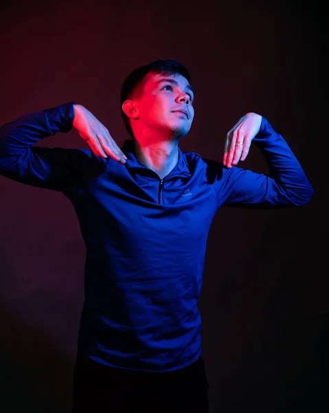 Un jeune homme en chemisier bleu dans le studio avec une lumière bleue et rouge — Photo