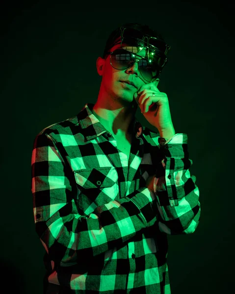 Młody mężczyzna w koszuli w kratę w studiu z czerwonym i zielonym światłem na czarnym tle — Zdjęcie stockowe