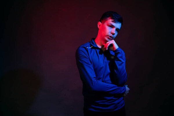 Emotions of a guy in a studio with blue and red light on a black background