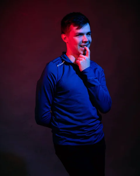Un jeune homme en chemisier bleu dans le studio avec une lumière bleue et rouge — Photo
