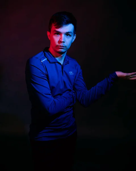 Émotions d'un gars dans un studio avec lumière bleue et rouge sur fond noir — Photo