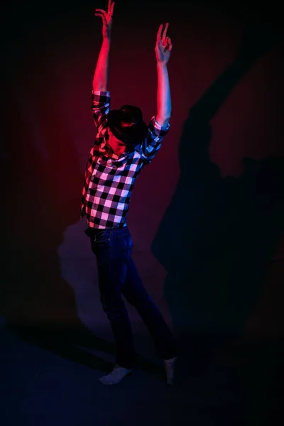 Un gars en chemise à carreaux avec un éclairage rouge et bleu dans le studio sur fond noir — Photo