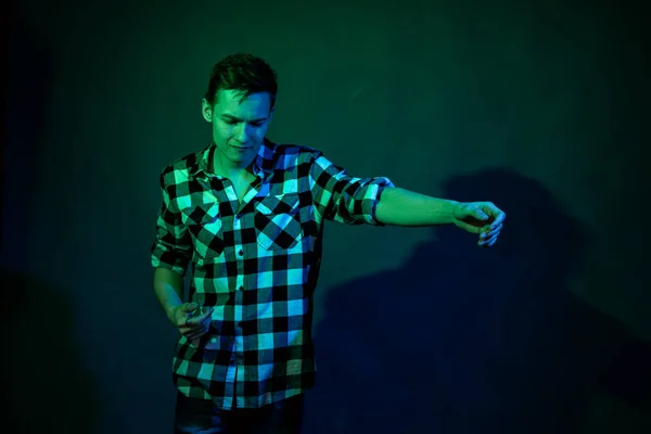 一个年轻人带着蓝光和绿光在演播室里跳舞 — 图库照片