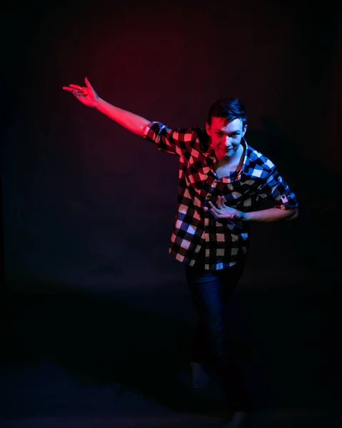 Un jeune homme dans un studio sur fond sombre avec une lumière multicolore — Photo