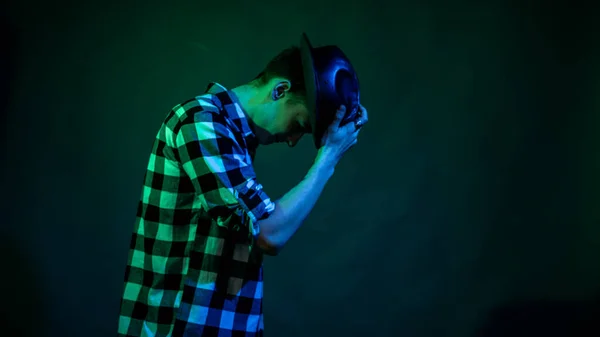 Młody mężczyzna tańczy w studio z niebieskim i zielonym światłem — Zdjęcie stockowe
