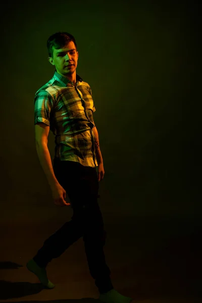 Le type en chemise à carreaux danse, illuminé par la lumière orange et verte — Photo