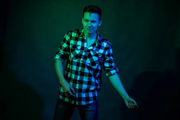 一个年轻人带着蓝光和绿光在演播室里跳舞 — 图库照片
