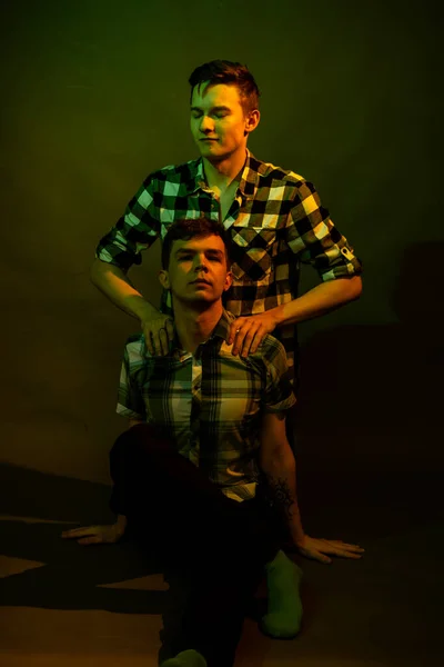 Zwei Jungs, die im Studio auf dem Boden sitzen. durch gelbes und grünes Licht beleuchtet — Stockfoto