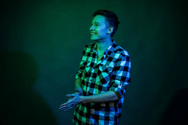 Un jeune homme dans un studio sur fond sombre avec une lumière multicolore — Photo