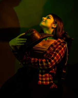 Kız siyah bir sandalyede oturuyor. Renkli ışıkla aydınlatılmış.