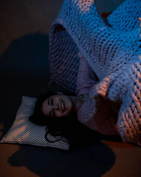 Das Mädchen liegt auf dem Boden, bedeckt mit einem rosa Karo, erleuchtet von einem warmen Licht — Stockfoto