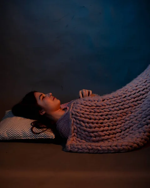 The girl lies on the floor, covered with a pink plaid, illuminated by a warm light — Stock Photo, Image