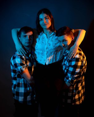 Ekose gömlekli iki adam, stüdyoda koyu renkli bir kızı tutuyorlar.