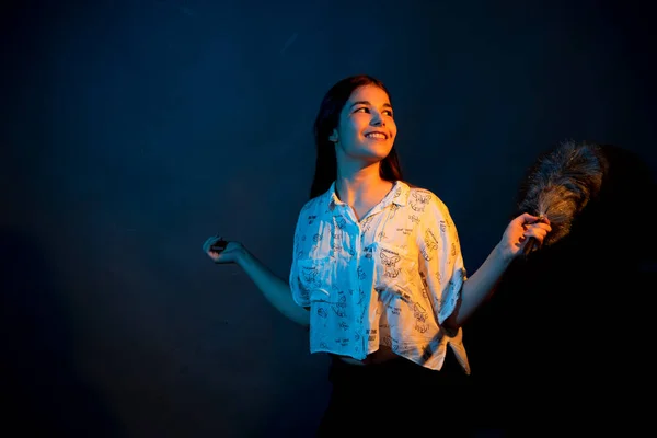 Girl in white shirt with dust brush on a dark background with colored light — Stock Photo, Image