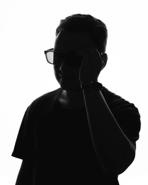 Die Silhouette eines jungen Mannes mit Brille auf weißem Hintergrund Stockbild