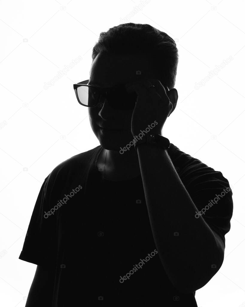 The silhouette of a young man wearing glasses on a white background