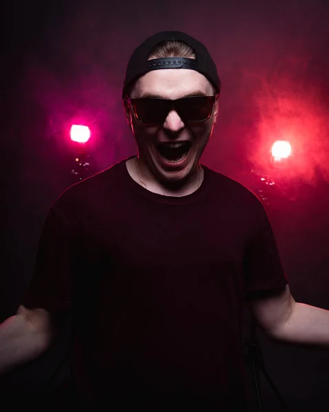 Ett porträtt av en skrikande kille mot en mörk bakgrund. belyst av röda lyktor — Stockfoto