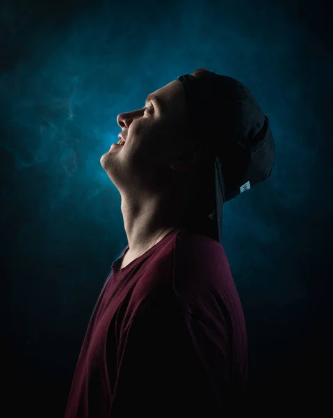 Portrait of a young man in a cap looking up, in profile on a black background — Stock Photo, Image