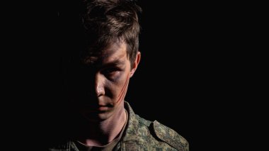 Siyah bir arkaplanda yarı yüzlü ve savaş boyalı bir askerin yakın plan portresi.
