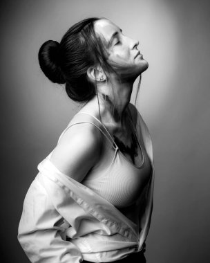 Yüzünde gri bir arkaplan olan bir kızın siyah beyaz portresi.