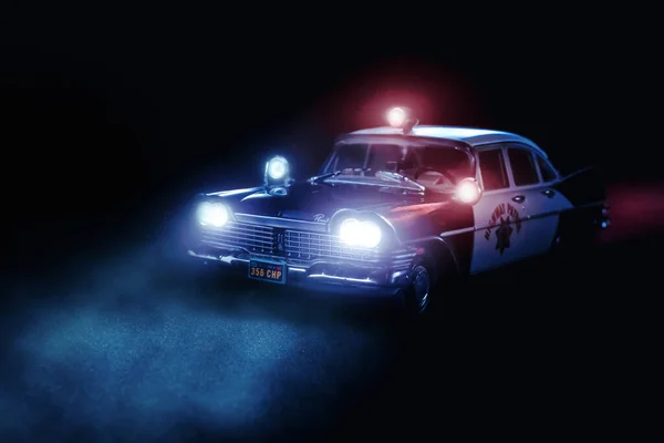 Spielzeugmodell des Polizeiautos von Plymouth auf schwarzem Hintergrund mit eingeschalteter rot-blauer Sirene — Stockfoto