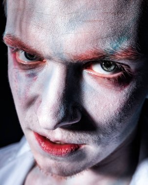 Yüzünde koyu bir arka planda ağlayan şakacı bir psikopatın yakın plan portresi.