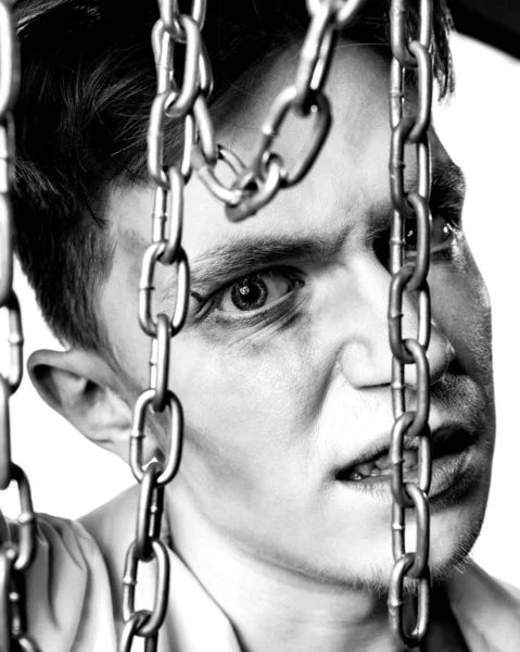 Retrato en blanco y negro de un maniático sosteniendo una cadena delante de su cara y sonriendo brutalmente sobre un fondo blanco — Foto de Stock