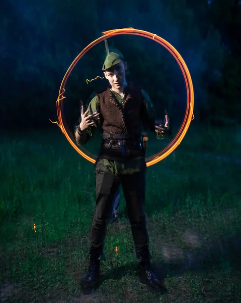 En kille i Robin Hood kostym står i bakgrunden av en brinnande fackla — Stockfoto