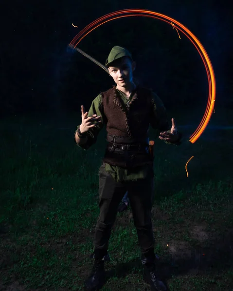 Facet w kostiumie Robin Hooda stoi w tle palącej się pochodni. — Zdjęcie stockowe