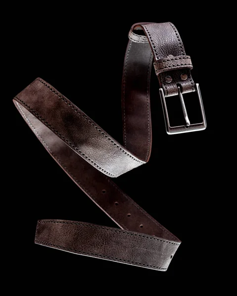 Cinturino in pelle marrone scuro strutturato con filo d'argento appeso in aria su uno sfondo nero — Foto Stock