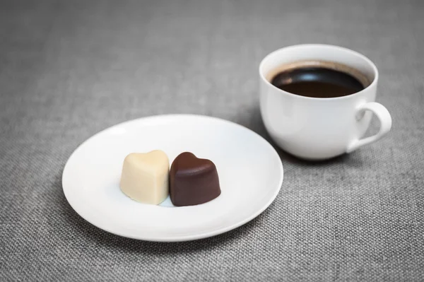 Cup of coffee and two heart-shaped chocolates — Stock Photo, Image