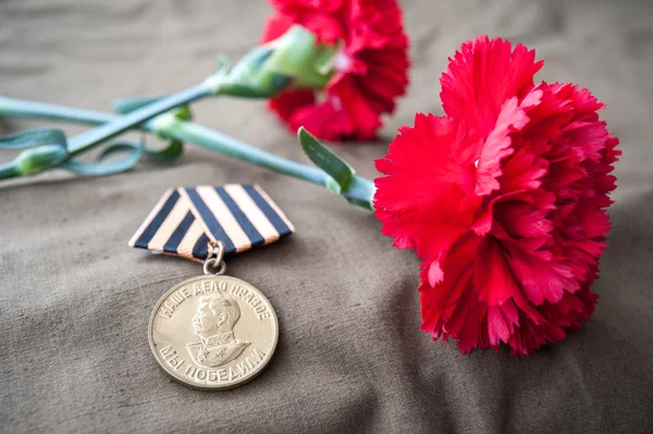 Медаль за перемогу над Німеччиною в Великої Вітчизняної війни 1941-1945 років і два червоних гвоздик — стокове фото