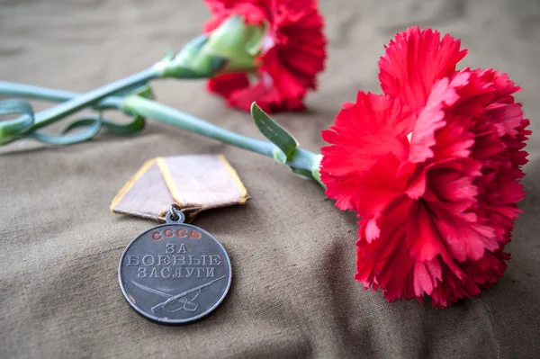 Медаль "За боевую службу" и две красные гвоздики — стоковое фото