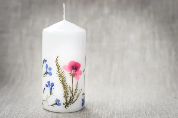 Свеча с цветами гербария на льняной ткани — стоковое фото