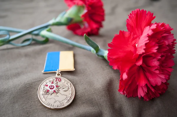 Medaille 70 Jahre Befreiung der Ukraine von den Nazis und zwei rote Nelken Stockfoto