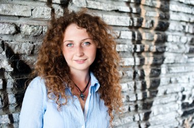 Güzel kız duruyor yakınındaki bir taş duvar.