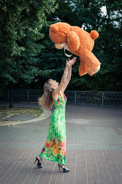 Hermosa mujer capturas grande y naranja juguete osito de peluche — Foto de Stock