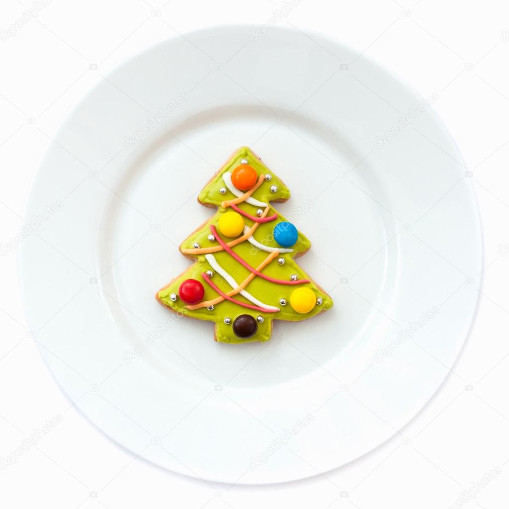 Christmas-tree gingerbread cookie on the plate on a white background.