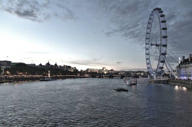 Thames nehrinin geniş açılı görüntüsü ve alacakaranlıkta Londra Gözü.
