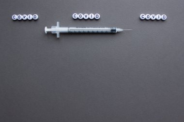 Covid-19 'a karşı aşı ve iğneli bir şırınga. Gri arka plan. Metin için boşluk
