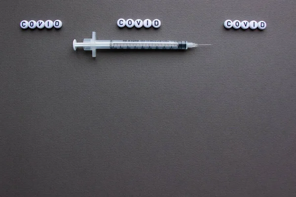 Covid-19 'a karşı aşı ve iğneli bir şırınga. Gri arka plan. Metin için boşluk